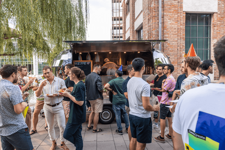 A small crowd standing next to a pizza truck at an event.