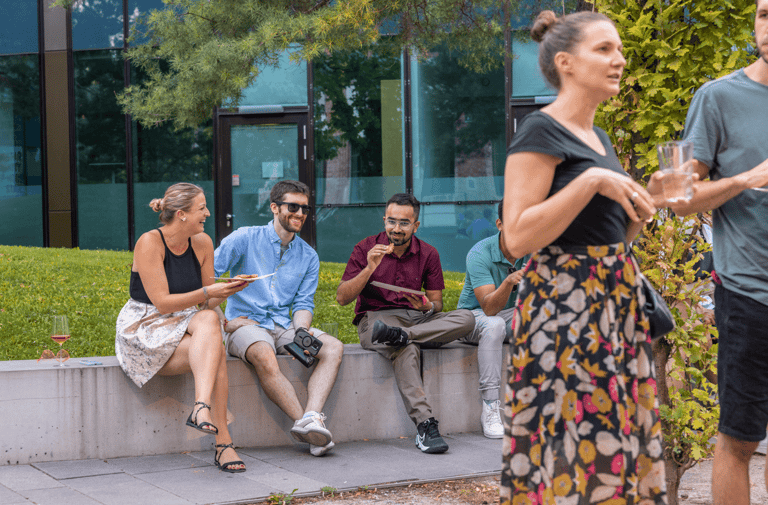 People sitting outside at an event, eating and talking.