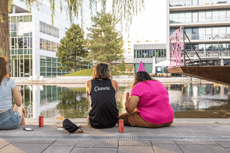 Two people sitting on the stairs talking, backs facing the camera. Water in front of them.