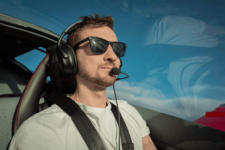 Young pilot in a private airplane on a sunny day with microphone, headphones and sunglasses.