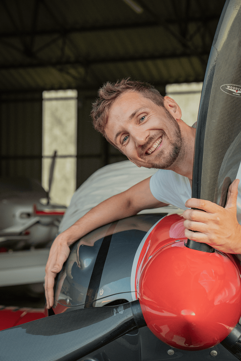 Young handsome man pilot hugging private plane propeller, smiling.