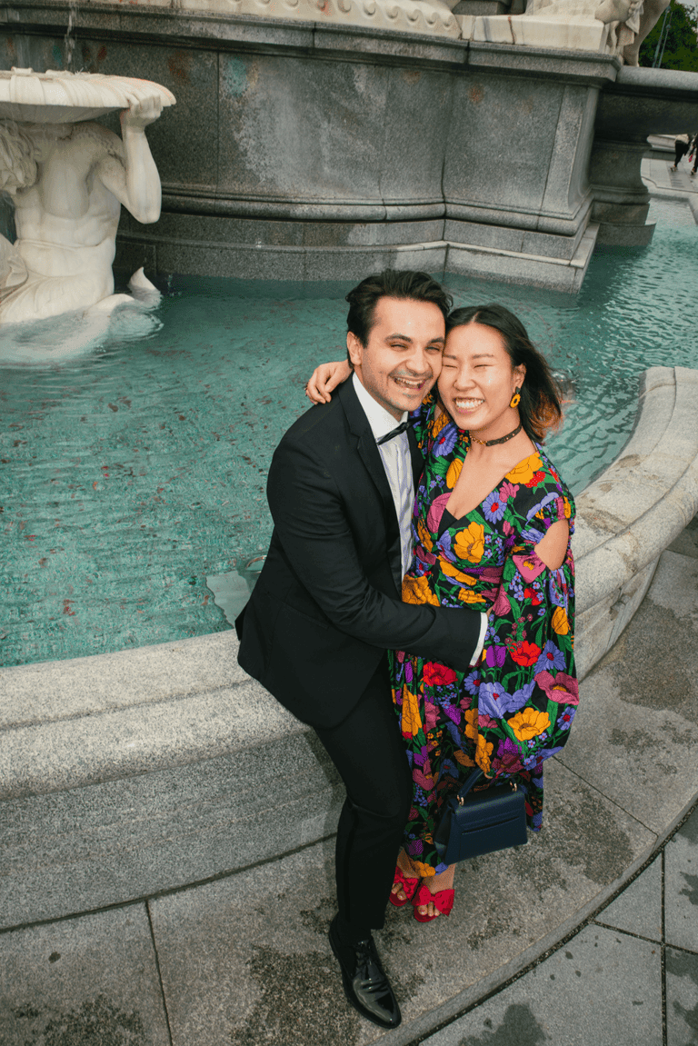 Young happy couple hugging romantically and smiling at a fountain.