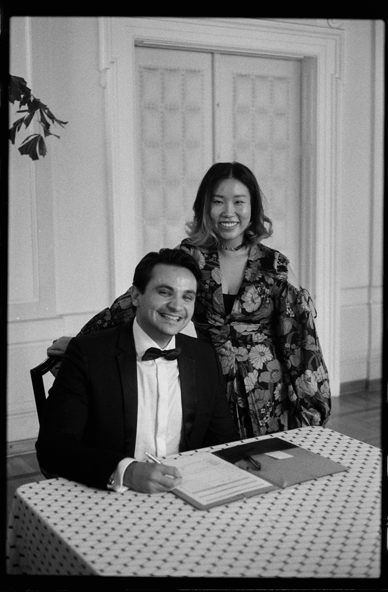 Young couple in festive clothes happy smiling after signing marriage papers. B&w film photography.