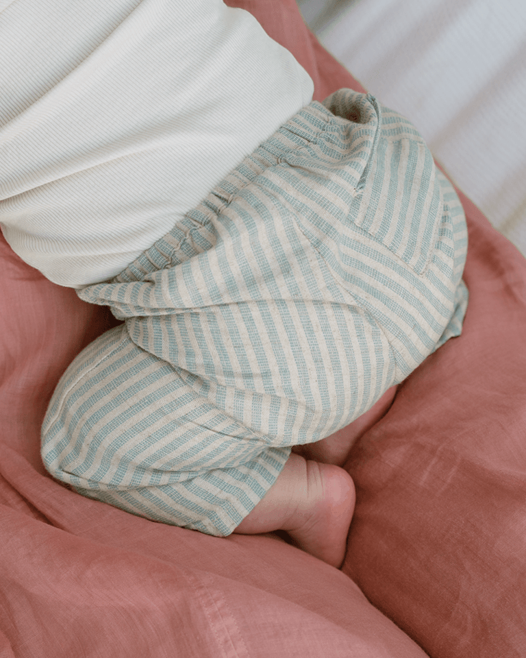 A close up shot of a baby resting in their mom's lap, scrunched.