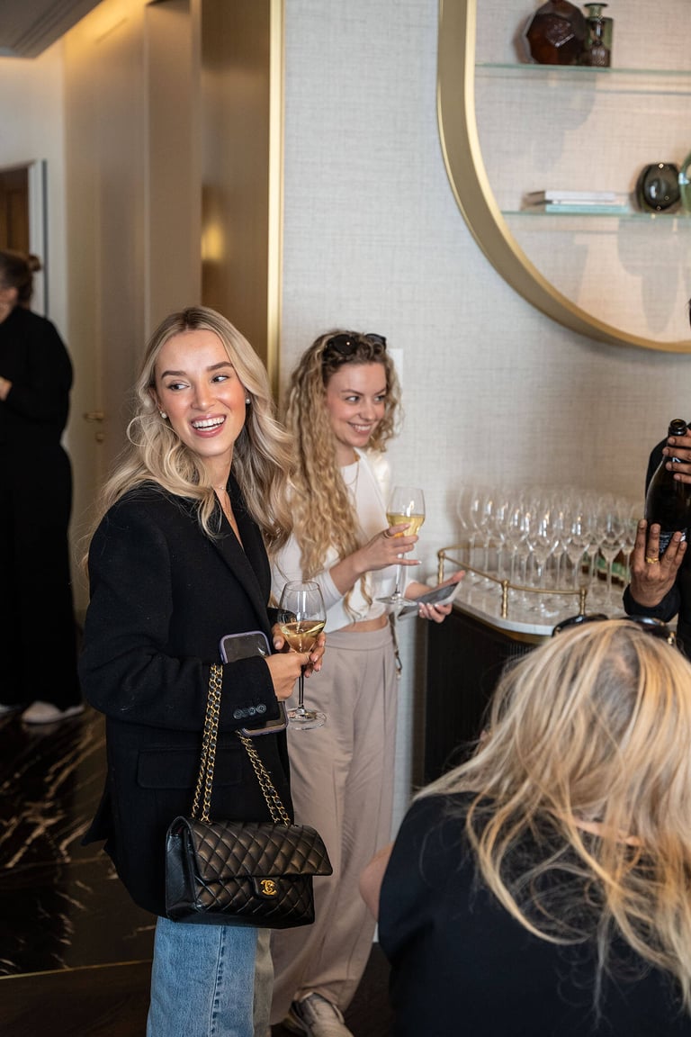 Influencer smiling at an event, holding glass of wine.