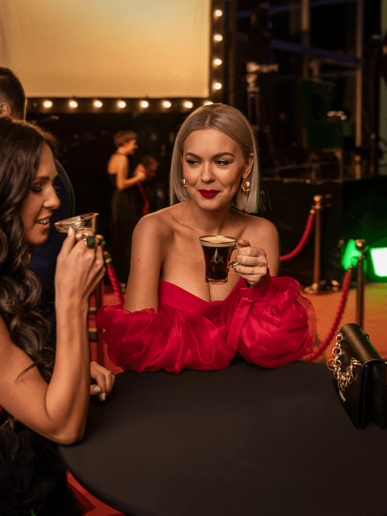 Lithuanian singer Monika Linkyte drinking coffee at a red carpet event.