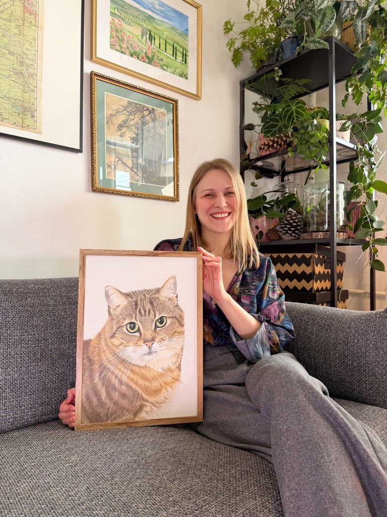 Pet portrait artist posing with a framed A3 realistic cat portrait