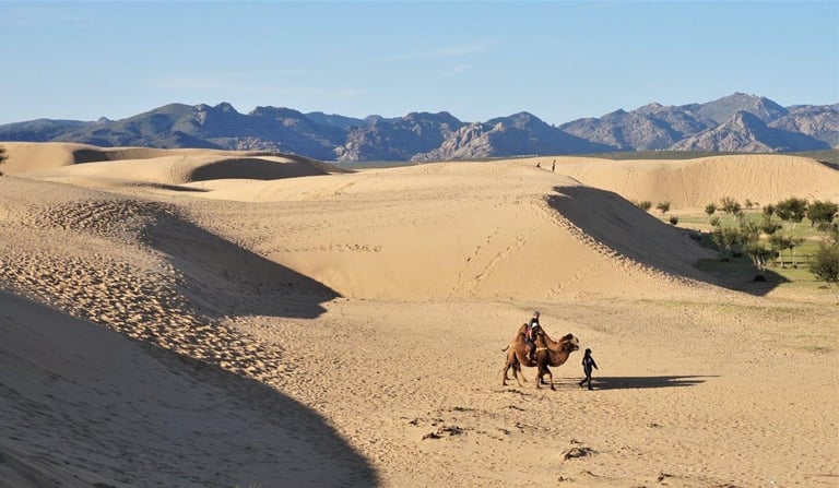 Riding a two-humped camel across the sand dunes of the Gobi