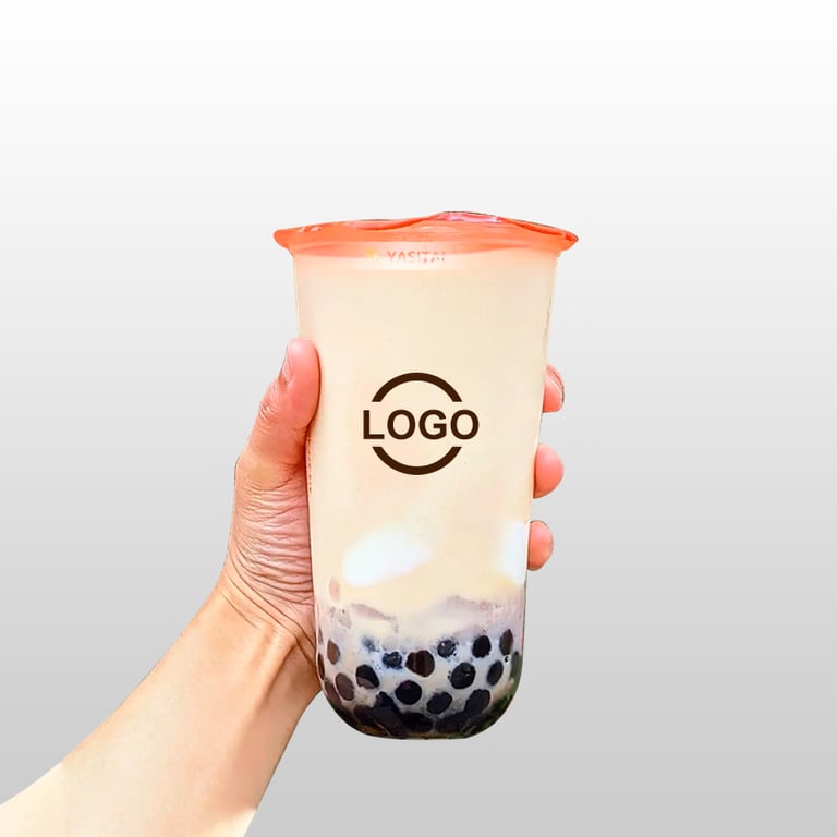 Hand holding a milk bubble tea cup with black tapioca pearls and cream foam against a plain background.