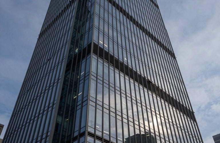 A wide-angle shot of a modern glass skyscraper reflecting a steel blue dusk sky. Mist white highlights on the sharp architectural lines.