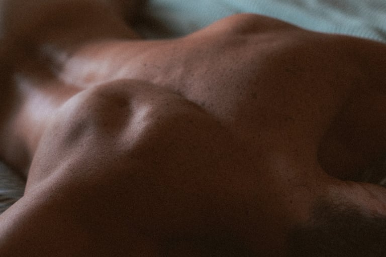 Photo boudoir homme nu en studio, lumière tamisée — Belle Tronche Montréal - Gros plan peau, muscles dos