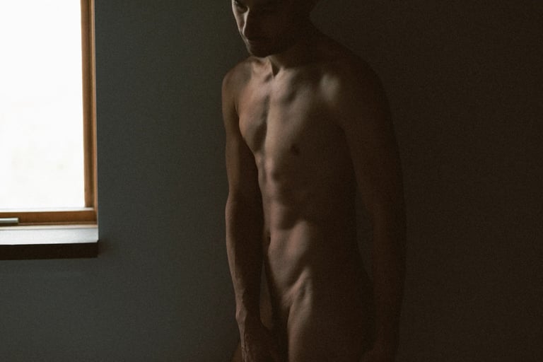 Photo boudoir homme nu en studio, lumière tamisée — Belle Tronche Montréal - Silhouette intérieur, fenêtre, profil