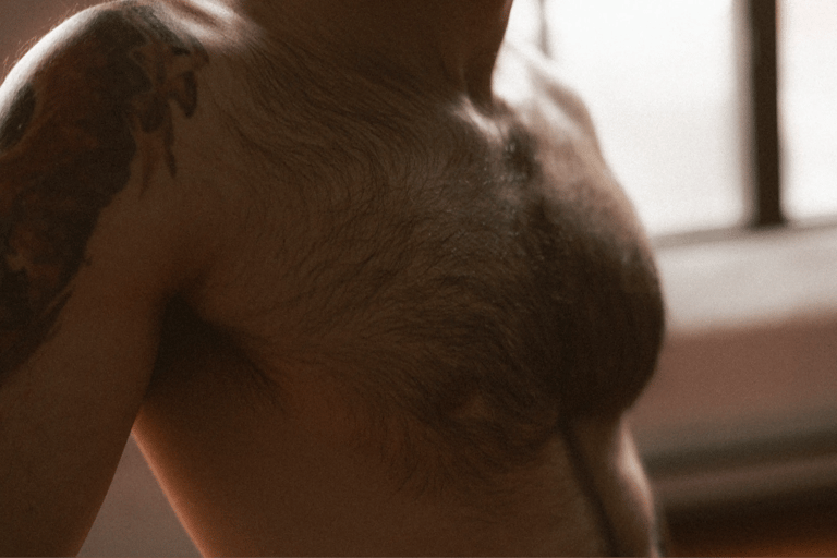 Photo boudoir homme nu en studio, lumière tamisée — Belle Tronche Montréal - Torse, peau, rivière, tattoo épaule