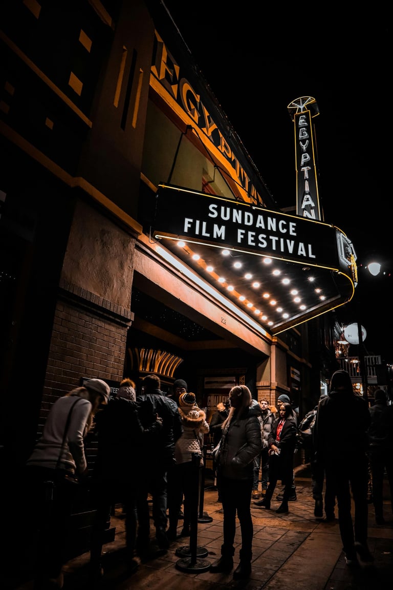 Crowd of people waiting outside the Egyptian Theatre under the Sundance Film Festival marquee at night.