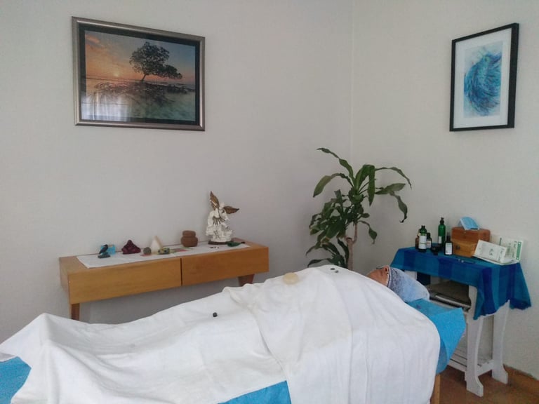 Sala de sanación holística, una persona en camilla de masaje recibiendo terapia energética en Oaxaca