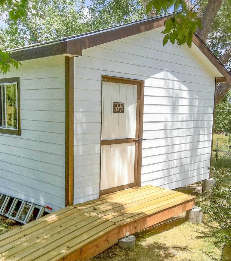 Completed custom storage shed with white siding and ramp built by Brewer Construction in Denver.