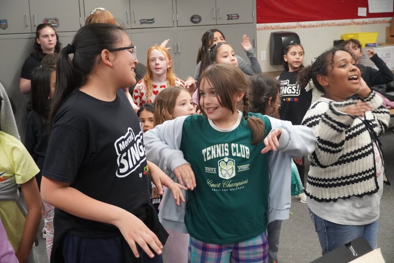 Diverse elementary students smiling and dancing together in a school classroom activity.