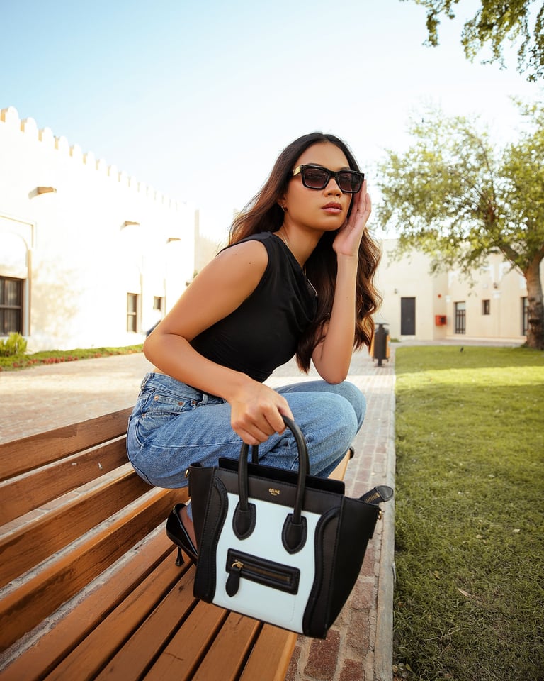 Jeune fille qui tient un sac Céline posé sur un banc