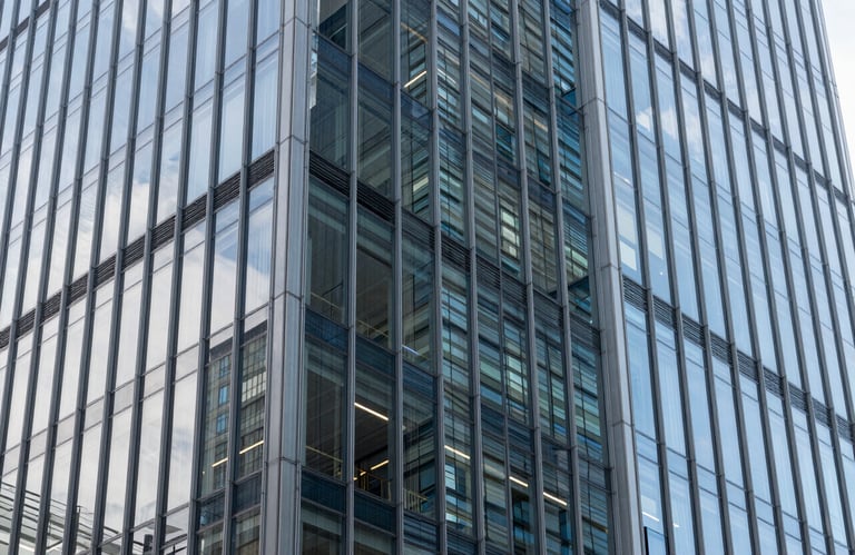 An architectural photography shot of a modern glass building facade in a North American business district, highlighting clean lines, transparency, and a professional, forward-thinking aesthetic.