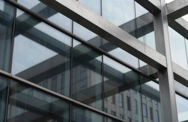 Close-up detail of a modern architectural facade featuring sleek glass panels and brushed steel beams, reflecting a charcoal and light gray palette.