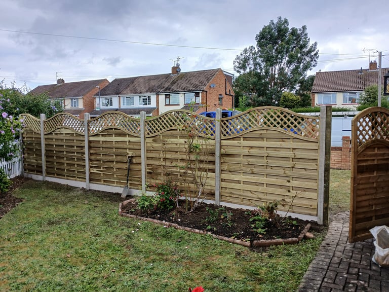 New wooden garden fence panels with decorative lattice trellis toppers installed in a suburban backyard.