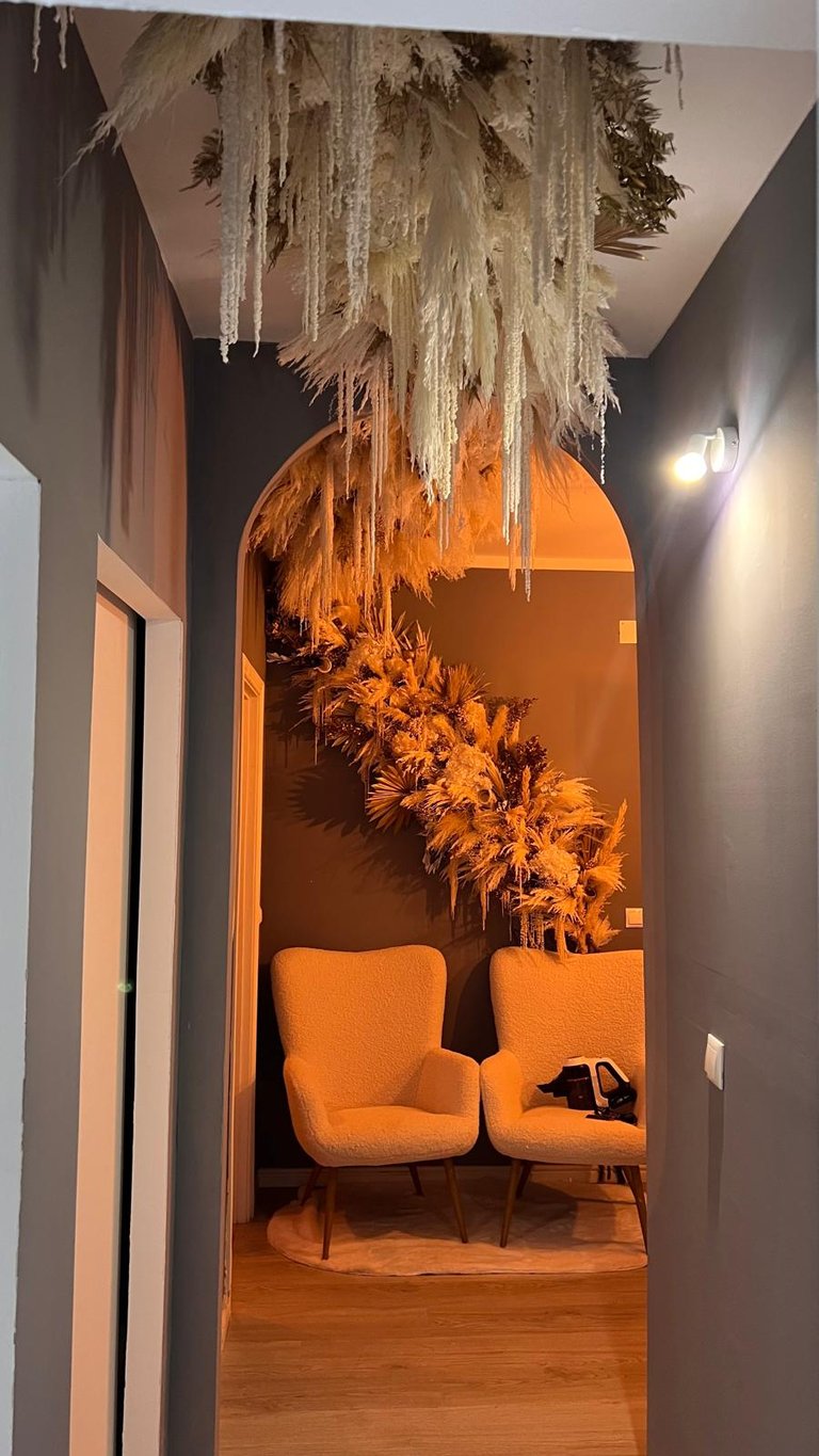 Modern hallway interior featuring pampas grass ceiling decor and white boucle accent chairs.
