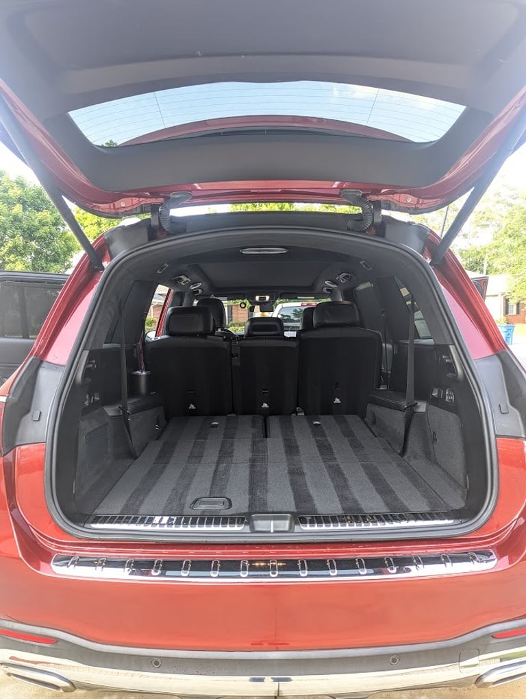 Spacious empty trunk of a modern red Mercedes SUV with folded rear seats showing cargo capacity.
