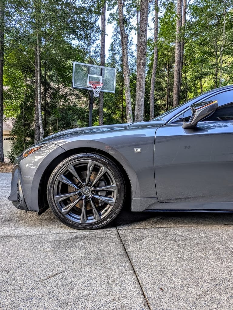 Side view of a grey Lexus IS F Sport showing the alloy wheel and Toyo tires parked in a driveway.