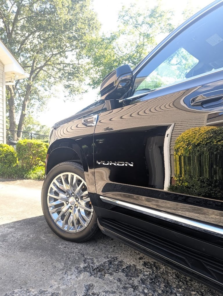 A black GMC Yukon SUV parked on a driveway, highlighting the polished exterior and chrome wheels.