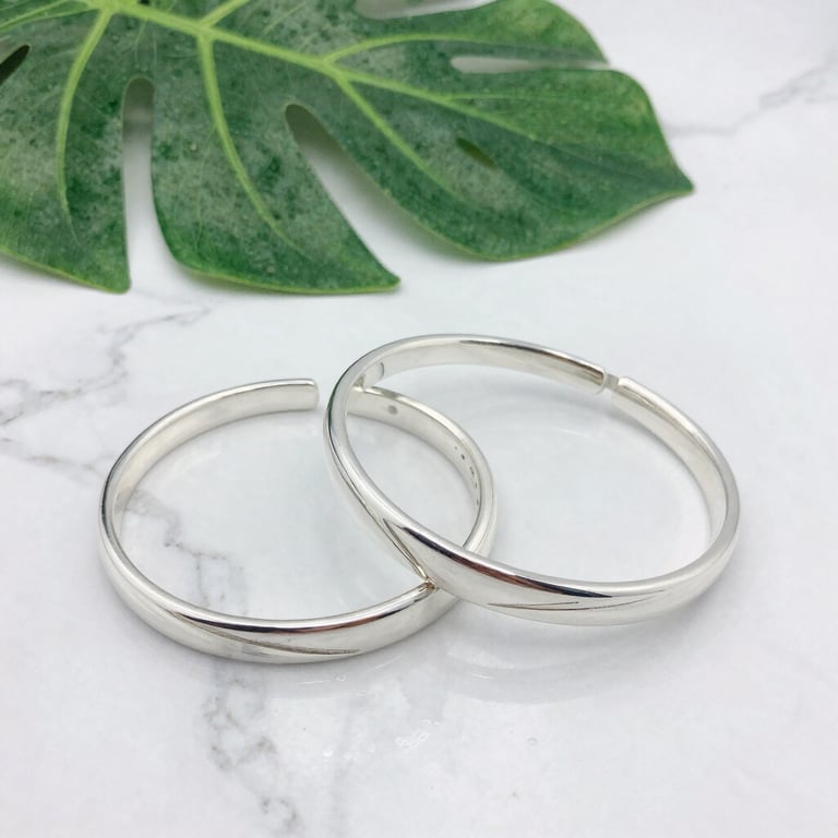 Set of silver bracelets with clean lines and a matte finish, arranged on a black velvet cloth.