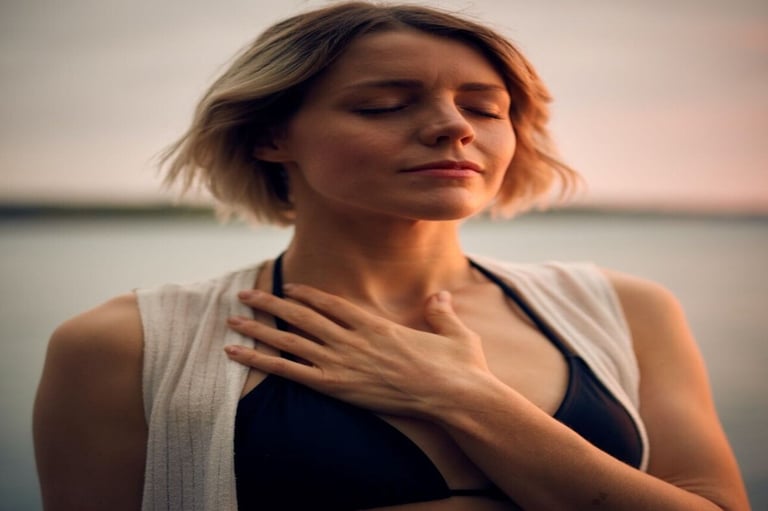 A peaceful woman practices mindfulness and deep breathing during a sunset meditation by the water.
