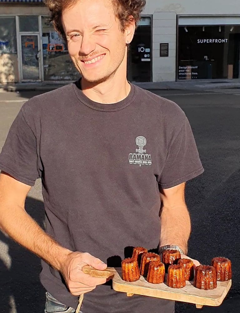Un homme tient une planche avec des cannelés dessus
