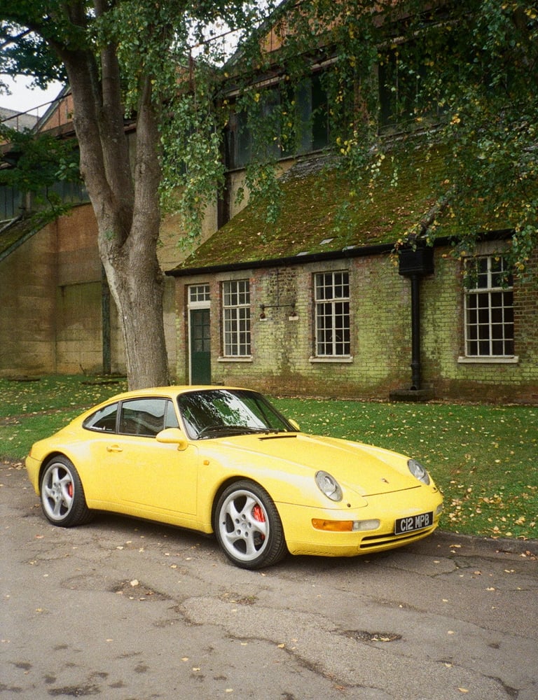 a yellow Porsche parked in front of a brick building
