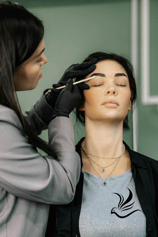 a woman is getting her eyebrows done by a professional makeup artist