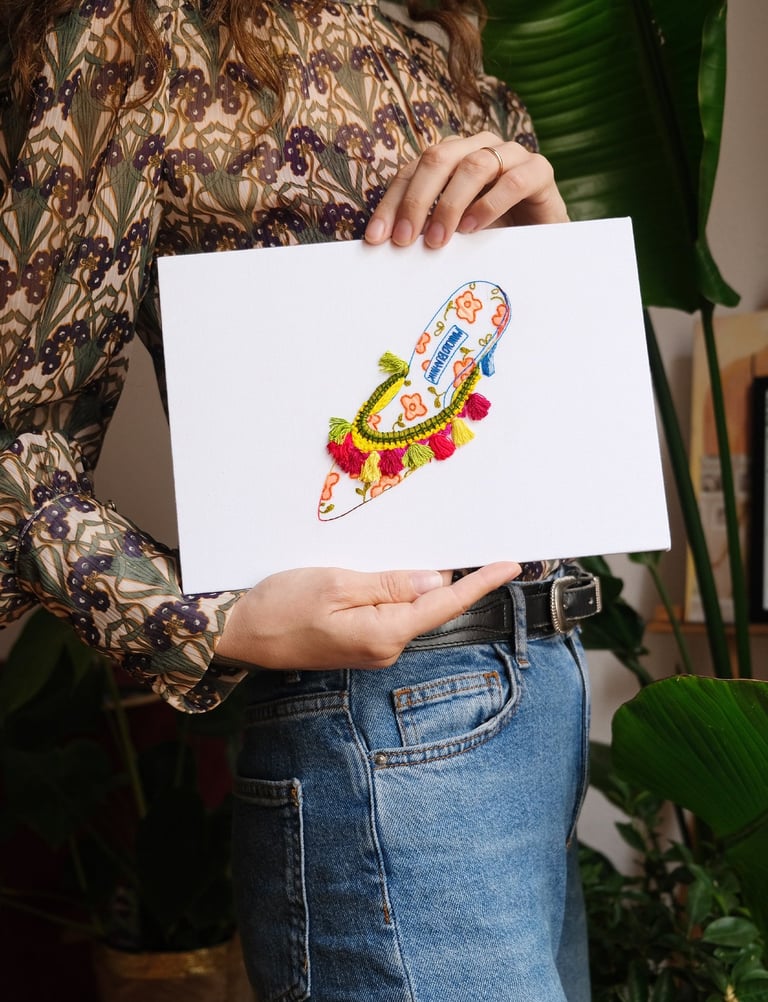 a woman holding a embroidery artwork of a woman heel
