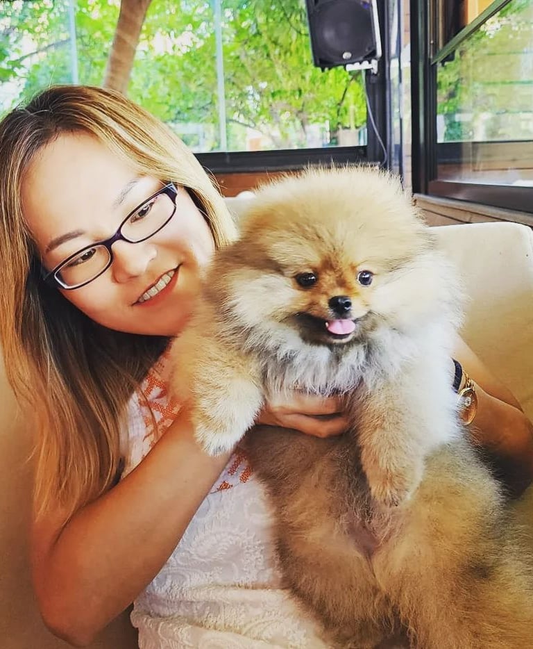 an asian woman in glasses and a white shirt is holding a dog