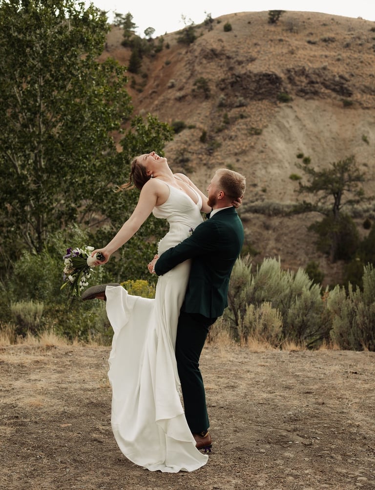 groom is holding a bride and spinning her around