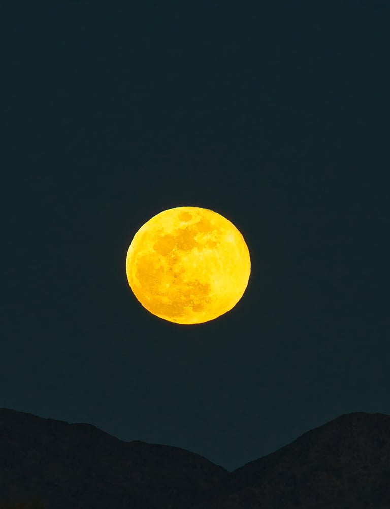 A glowing golden full moon shining brightly in a dark night sky above silhouetted mountain peaks.