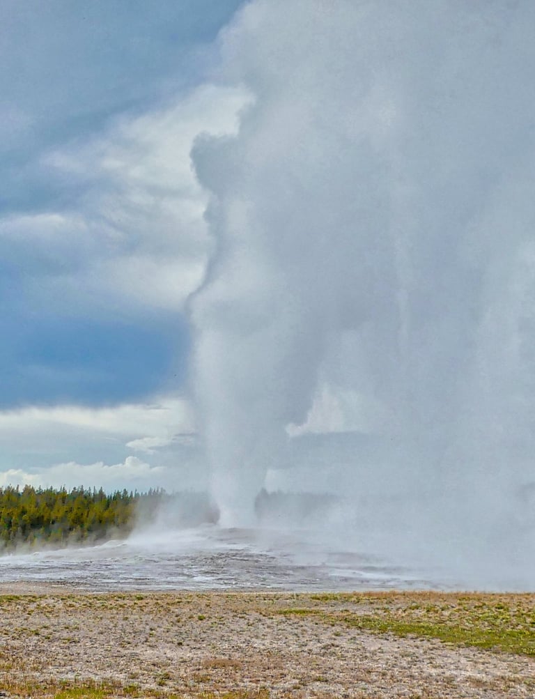 Old Faithful Geyser erupting with a massive steam column at Yellowstone National Park.
