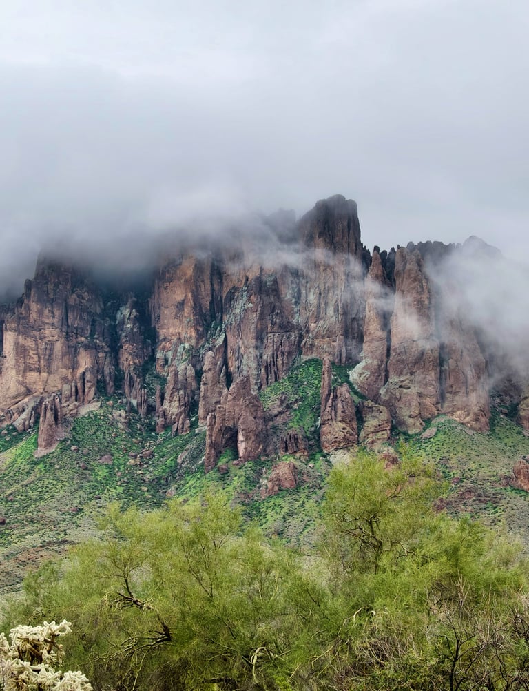 Misty fog rolling over the jagged peaks of the Superstition Mountains in Arizona's desert landscape.