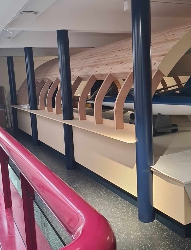Structure voûtée en bois courbé intégrée à un aménagement intérieur avec poteaux métalliques – réali