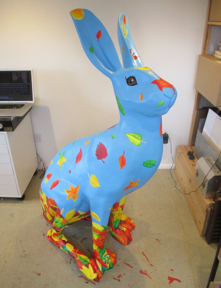 A hare sculpture with autumn leaves and wildlife painted by Laura Fearn