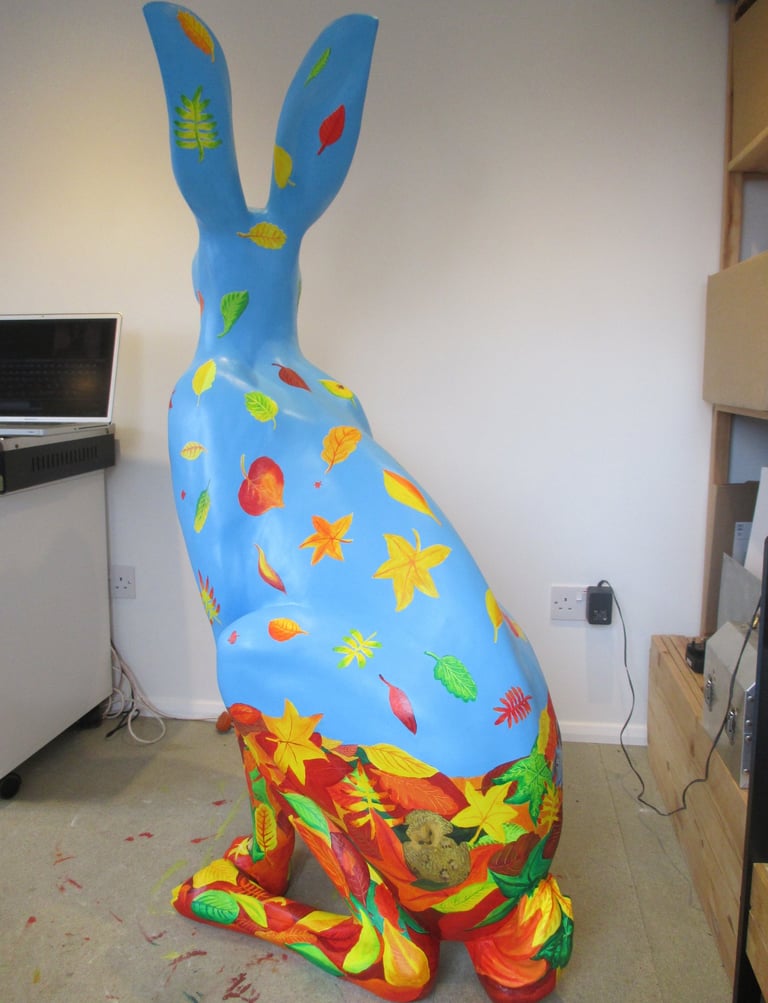 A hare sculpture with autumn leaves and wildlife painted by Laura Fearn