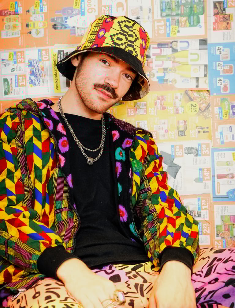 A man wearing colourful clothing, a necklace and a hat