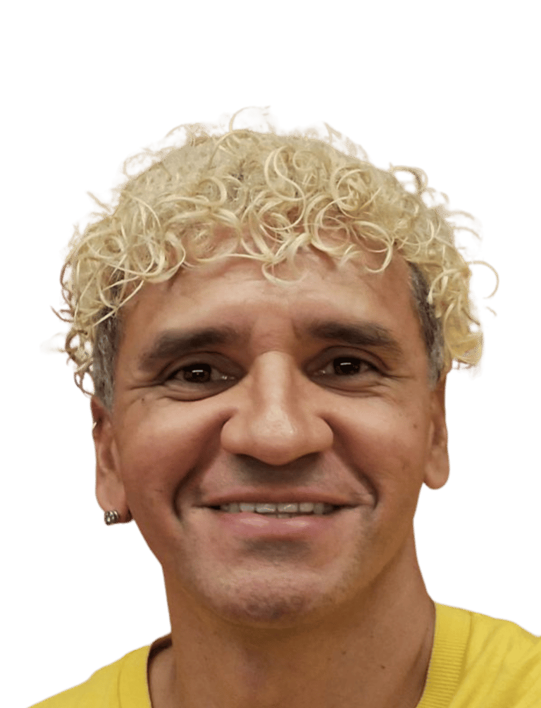 Smiling man with short blonde curly hair and a yellow shirt against a black background.