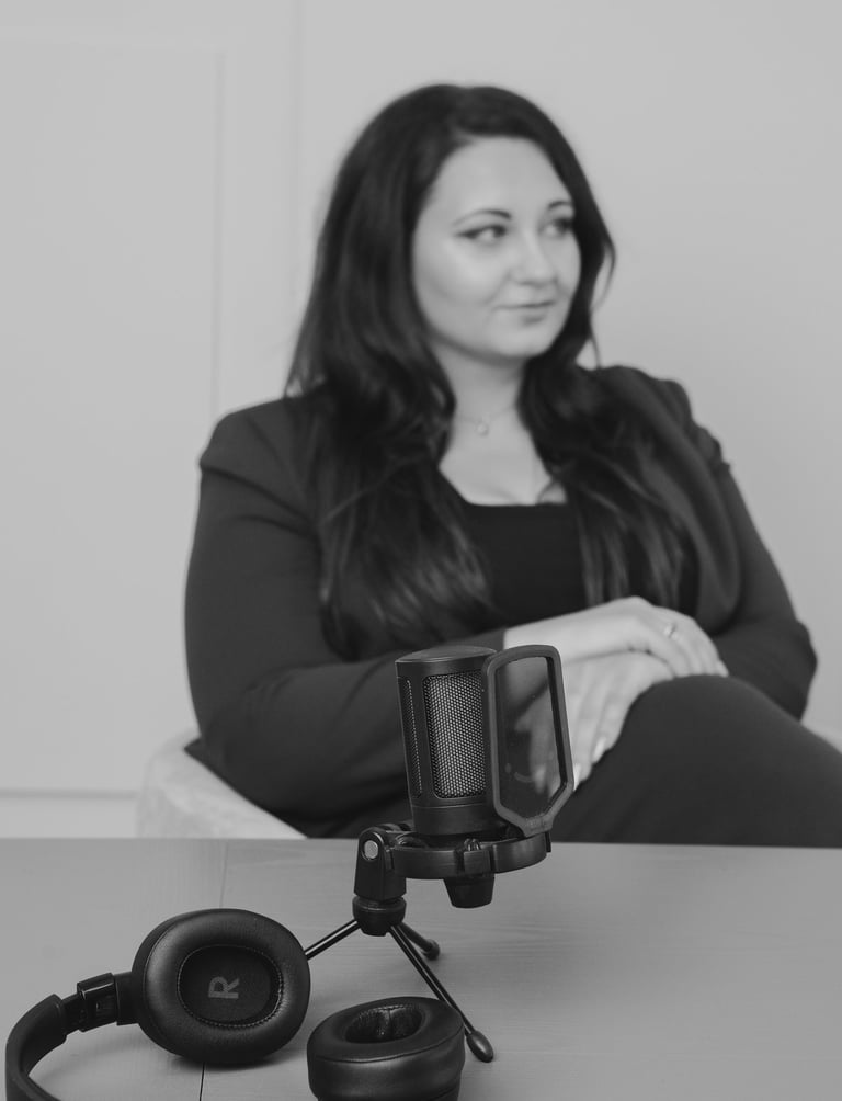 Professional condenser microphone and headphones on a table during a studio podcast recording session.