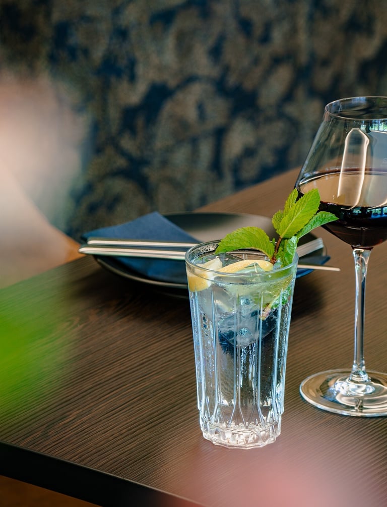 Erfrischender Wasser mit Minze und ein Glas Rotwein auf einem Restauranttisch.