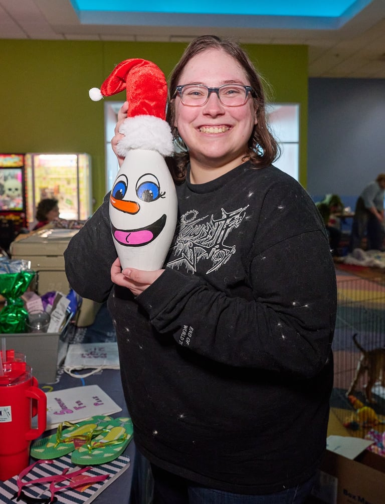 a woman holding a pin with painting and Santa hat