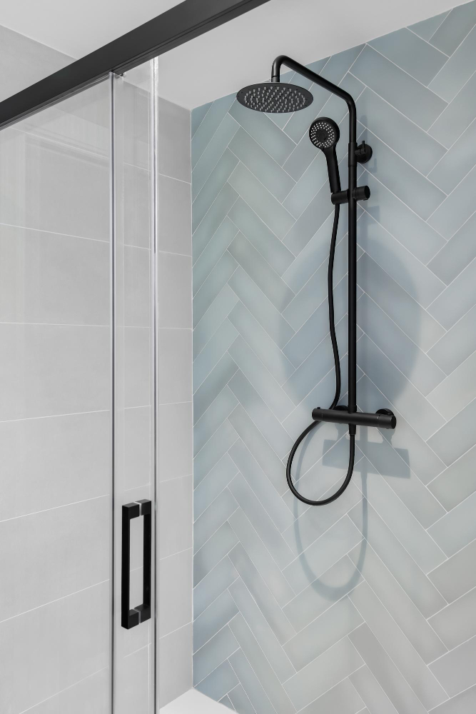 New frameless shower door with black handle and clean glass panels – demonstrates a completed shower