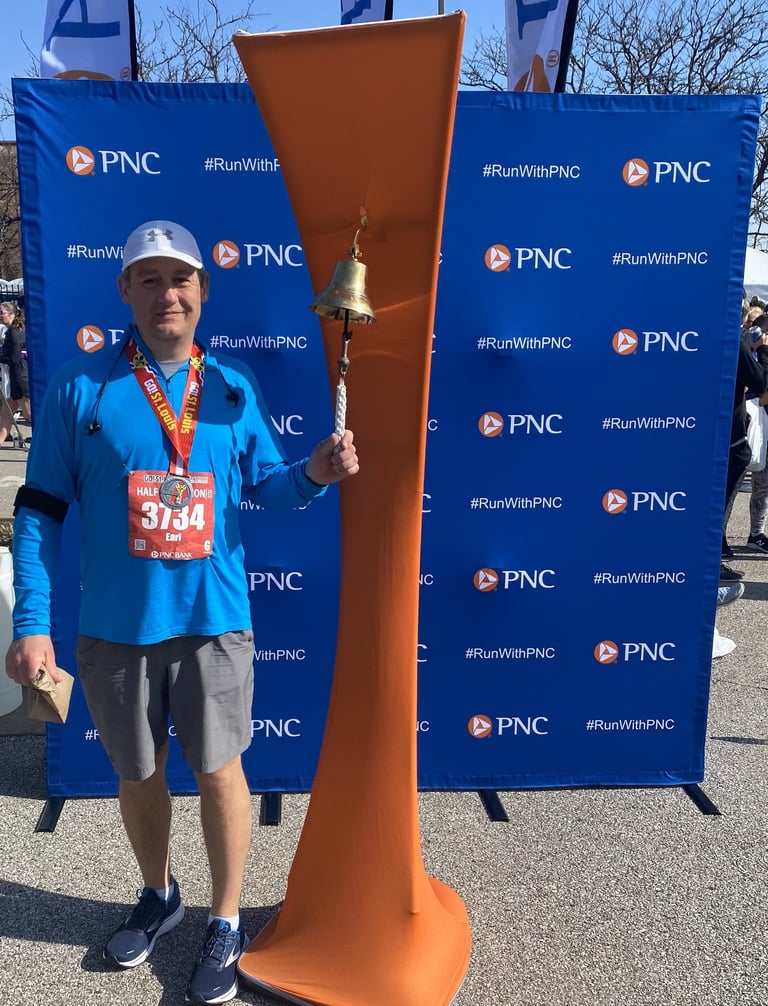 Man wearing a metal and running number, ringing a bell, posing for the camera
